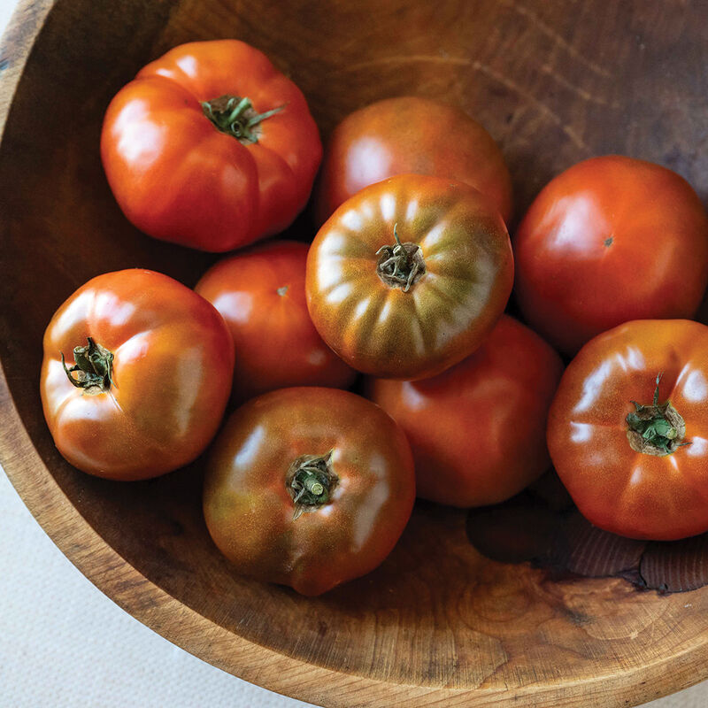 Ripe Black Angel tomatoes with mahogany shoulders in a wooden bowl