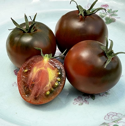 Ripe Black Prince tomatoes, including one cut open to show the dark interior